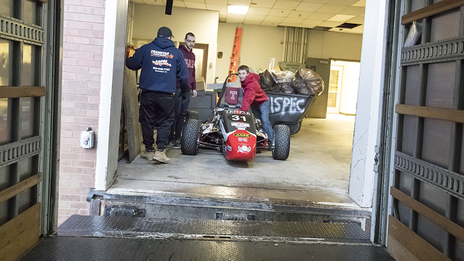 Two students pushing the race car towards a loading dock. 