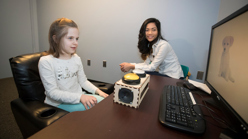 graduate student Zoe Ngo working with a child at a computer.