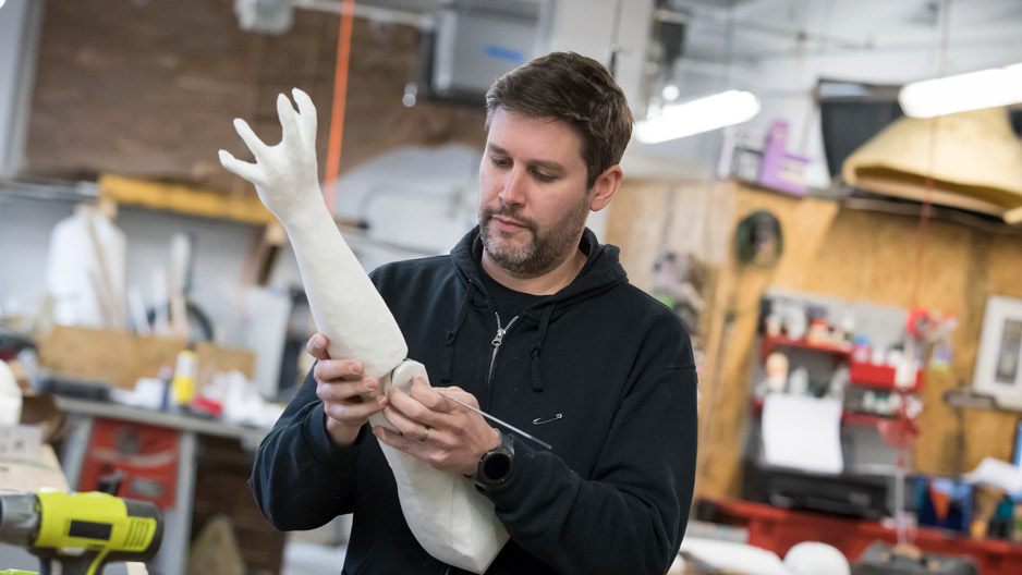 Michael Latini examining a puppet he's making for a Broadway show
