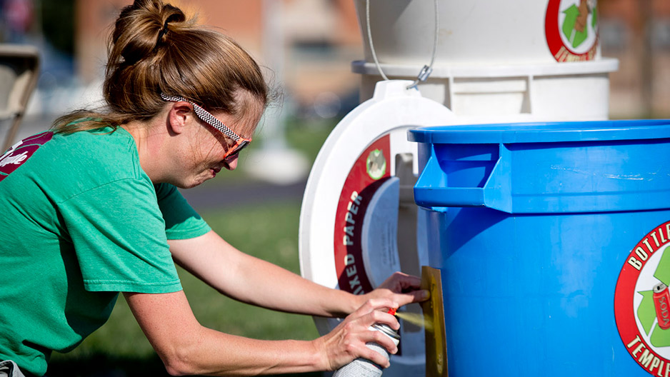 Kathleen Grady spray painting an address onto a recycling bin