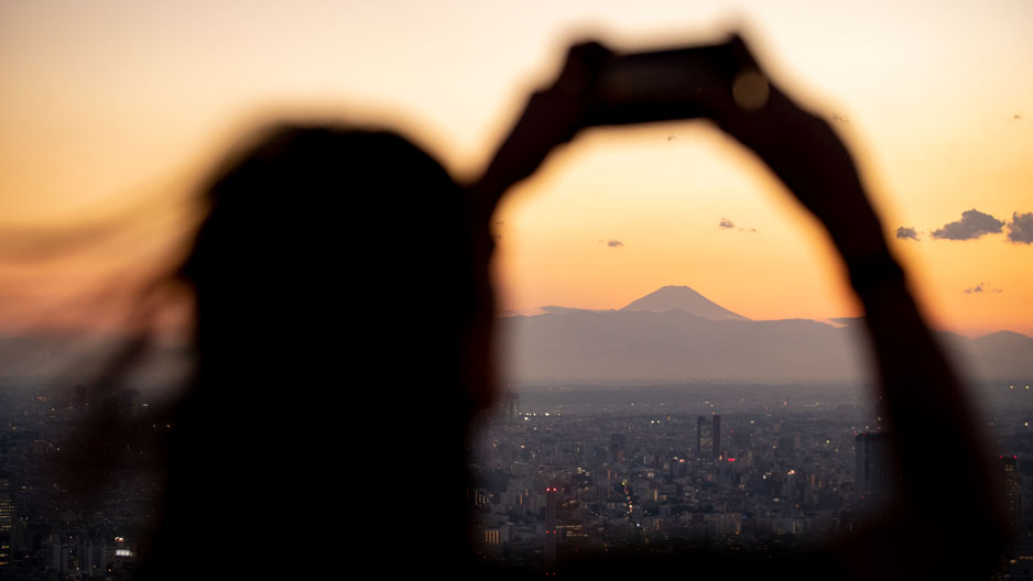 person holding phone up to take a photo of Mt. Fuji