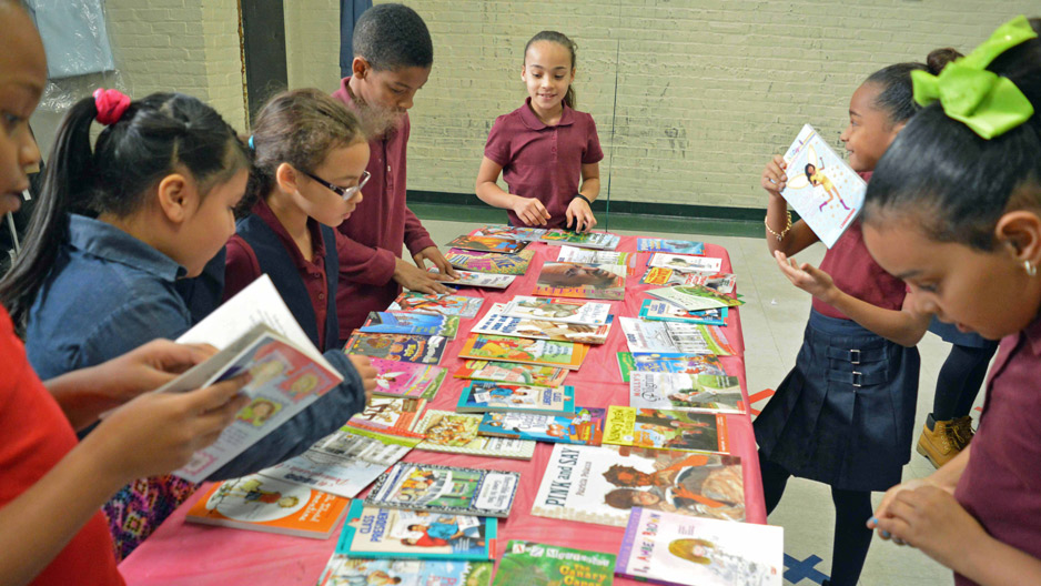 children standing at a table full of books.
