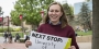 Hope Watson holding a sign that says "Next stop: University of Cambridge".