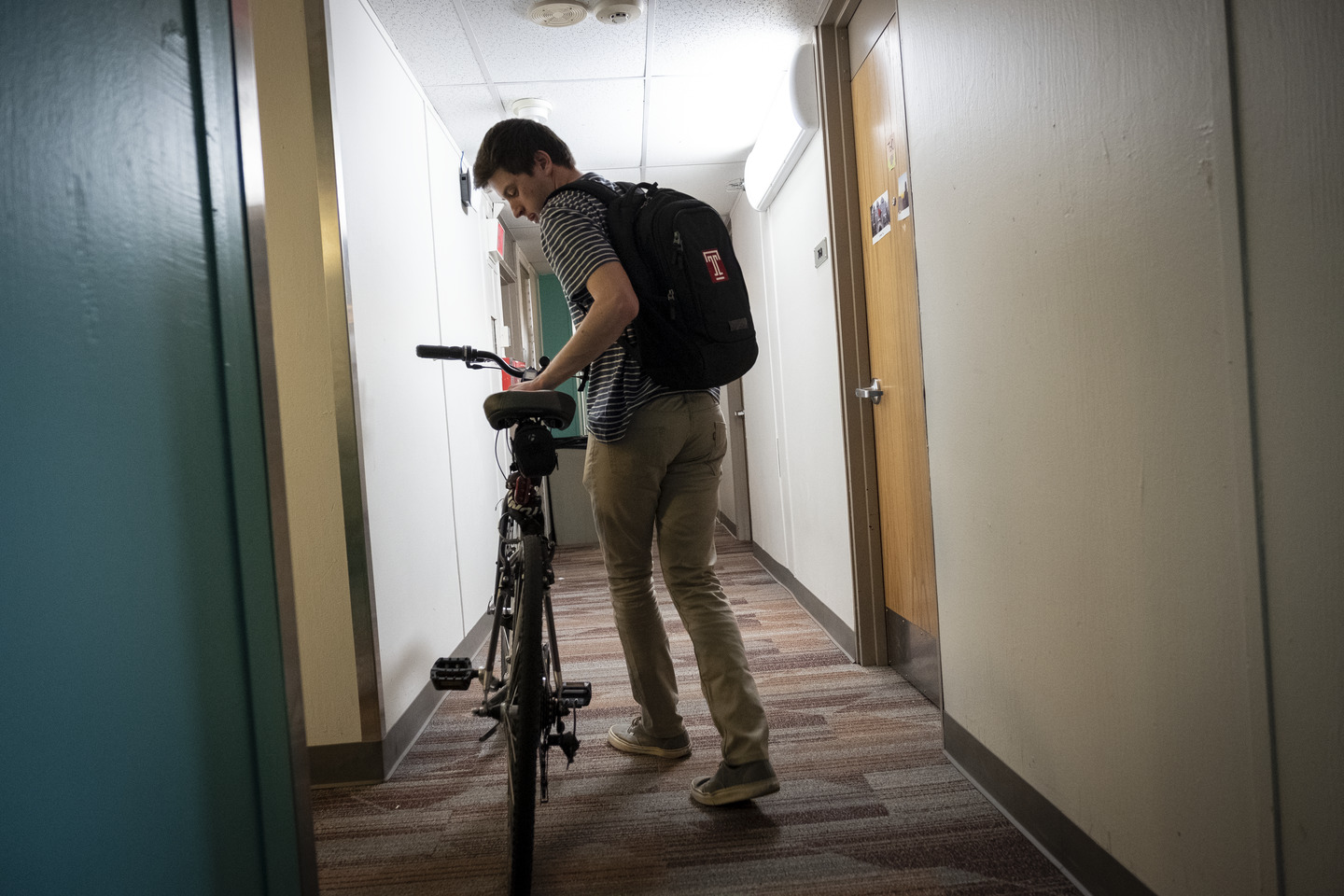 A student rolls his bike down the hallway of a residence hall 