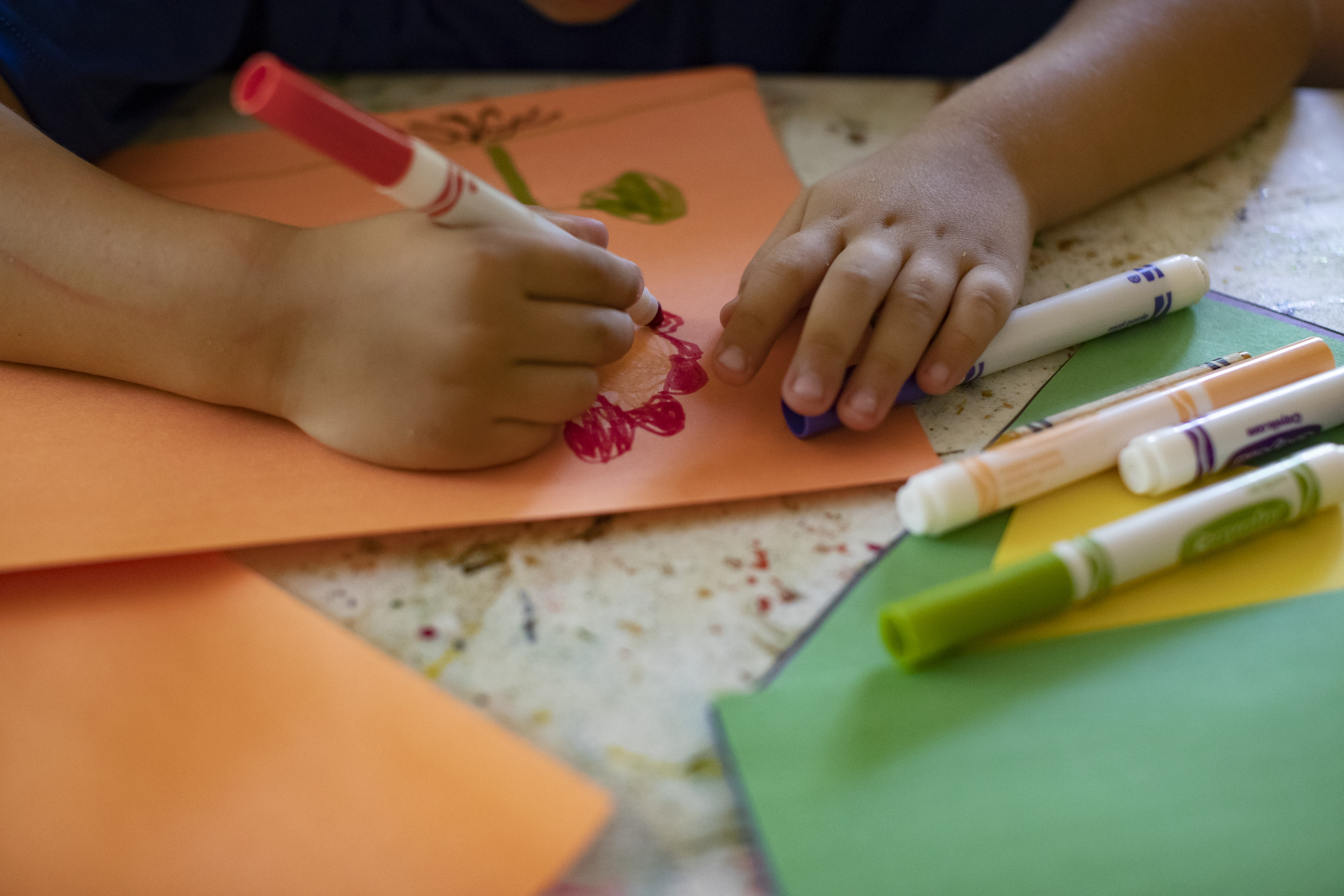 Picture shows hands of student drawing with colorful markers. The picture is used to illustrate for an article on trauma-informed schools.