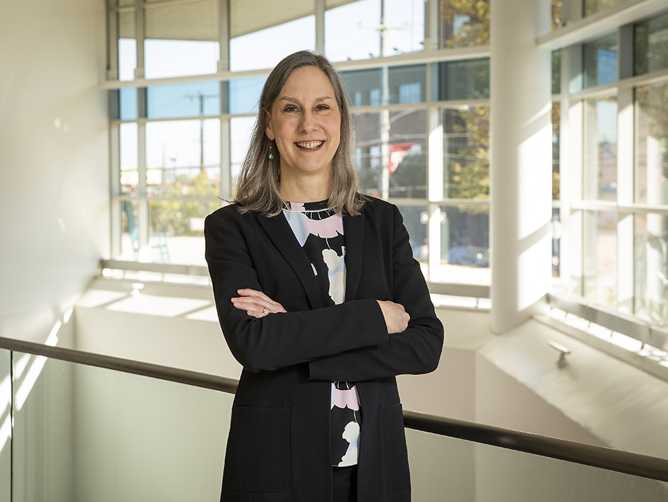 Portrait photo of Dr. Alison Reynolds in front of floor to ceiling windows