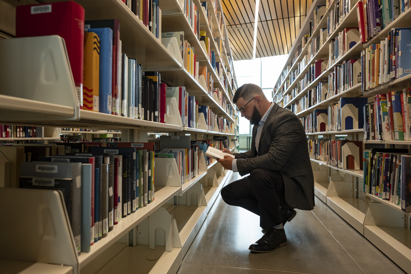 Image of student looking through bookshelves at Charles Library.