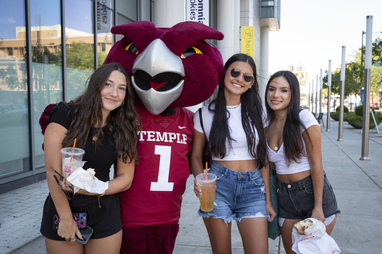 Three girls wearing T-shirts and shorts standing next to an Owl mascot.