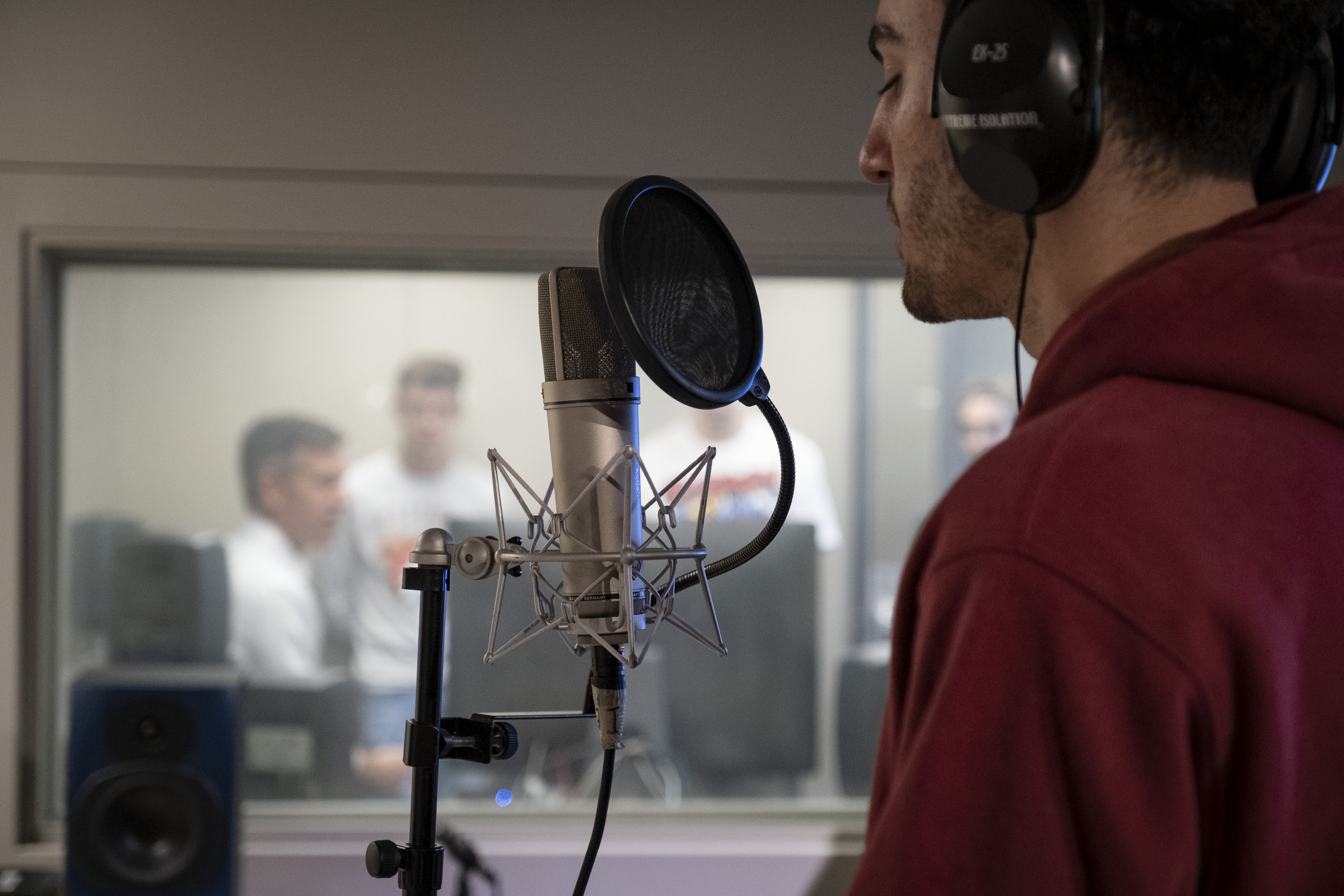 Performer in a recording booth singing into a microphone