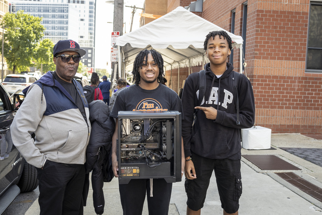 Student holds a computer he built and poses with his family