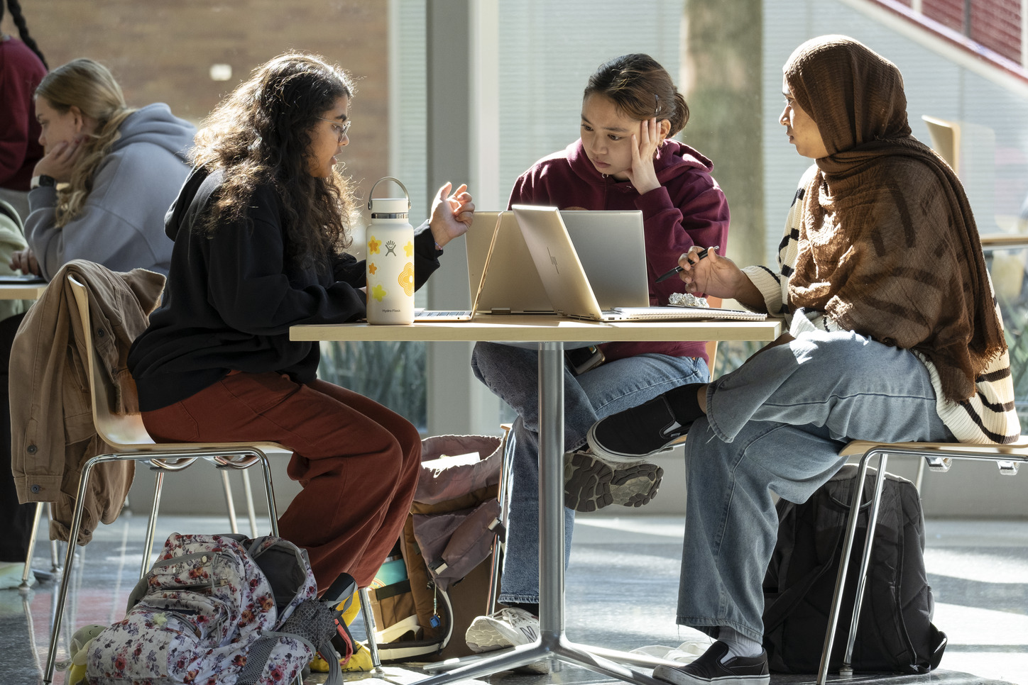 Three students at a table working on laptops