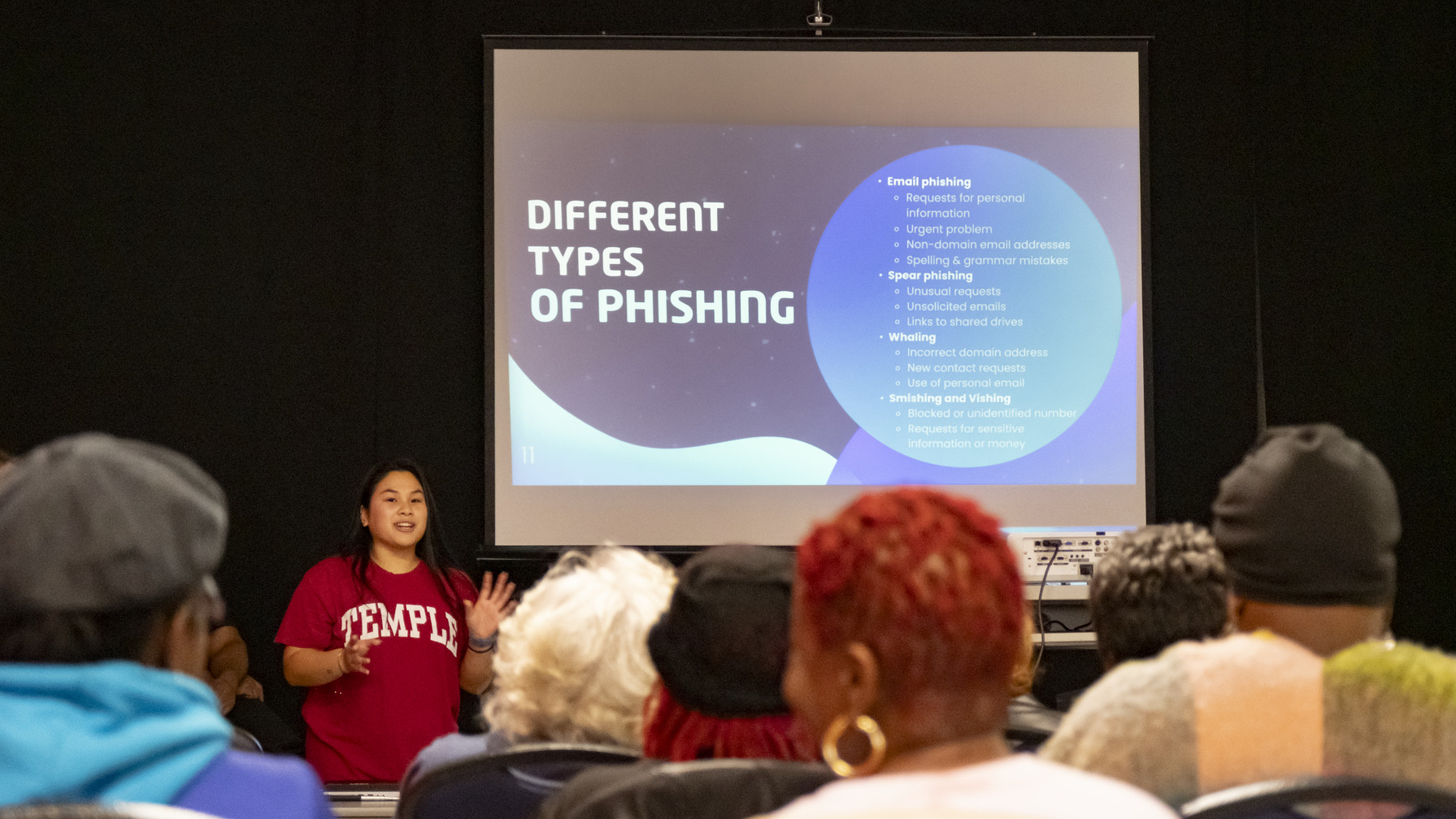 Image of a student wearing a cherry and white sweater speaking to the community.