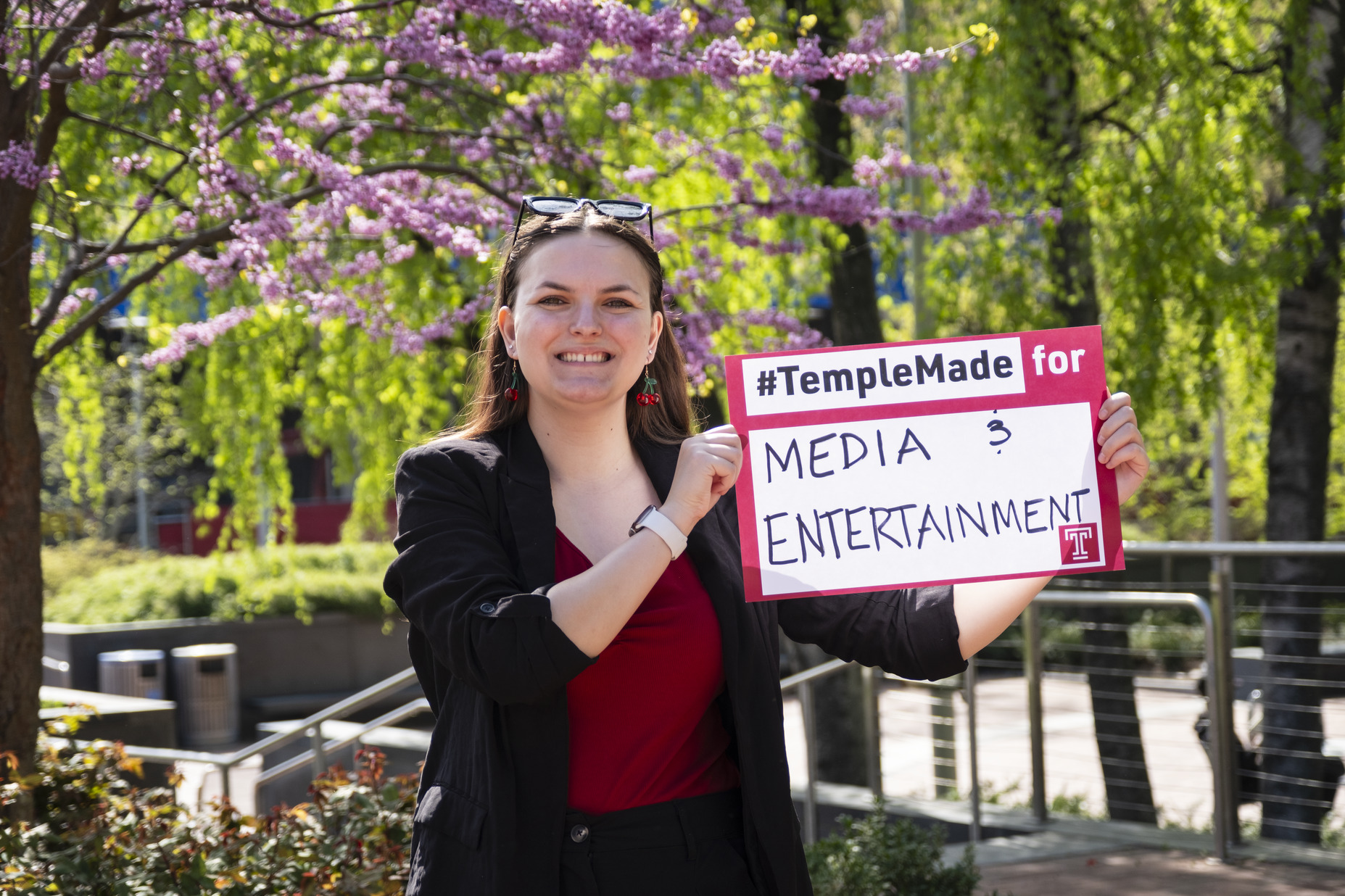 Image of Sydney Binkley holding a sign that reads "media & entertainment."
