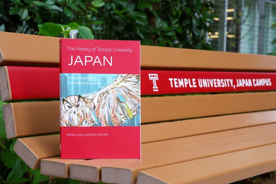 A copy of The History of Temple University Japan on a bench