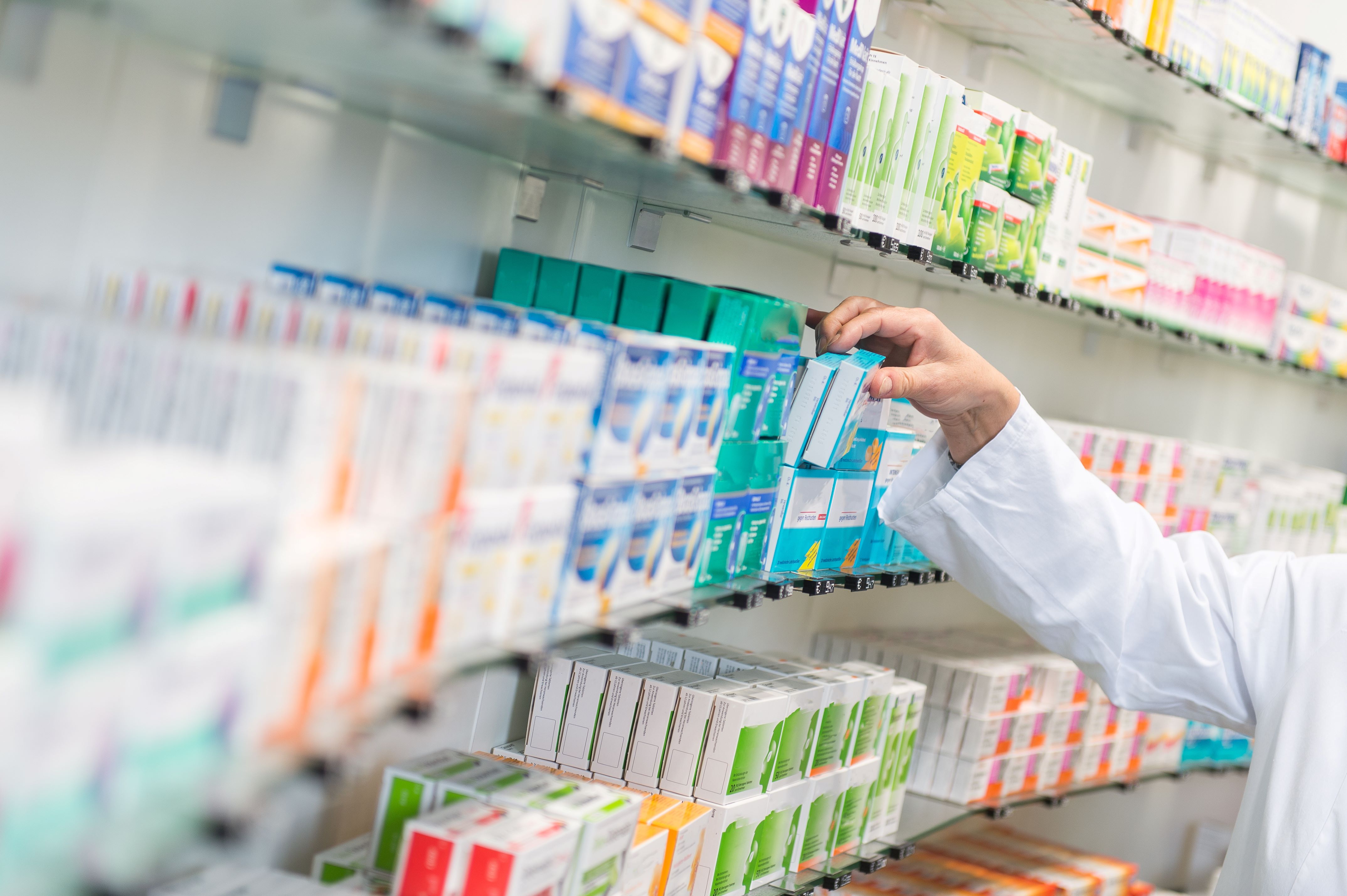 Pharmacist reaches for stock on a shelf