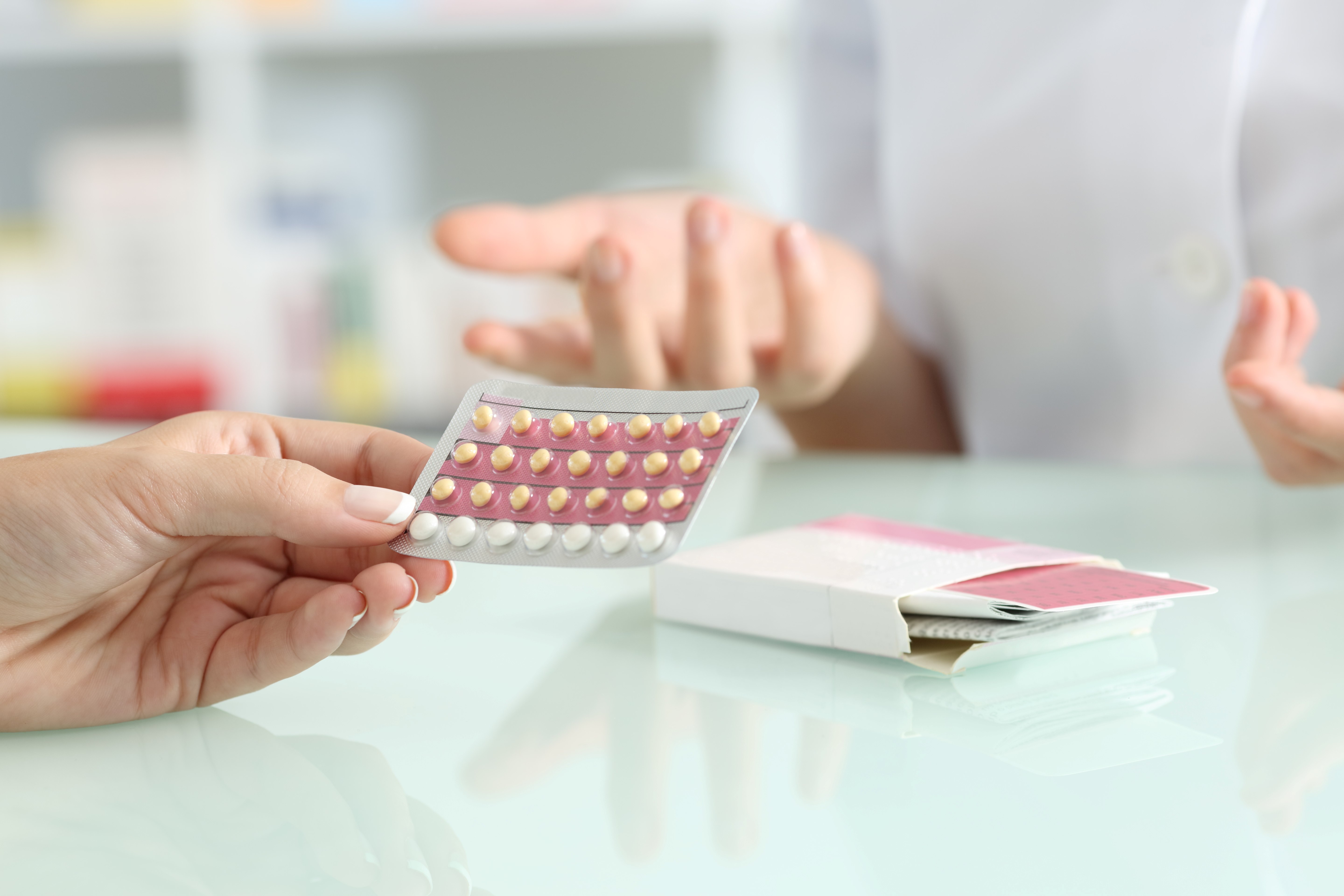 Doctor handing oral contraceptives to another person