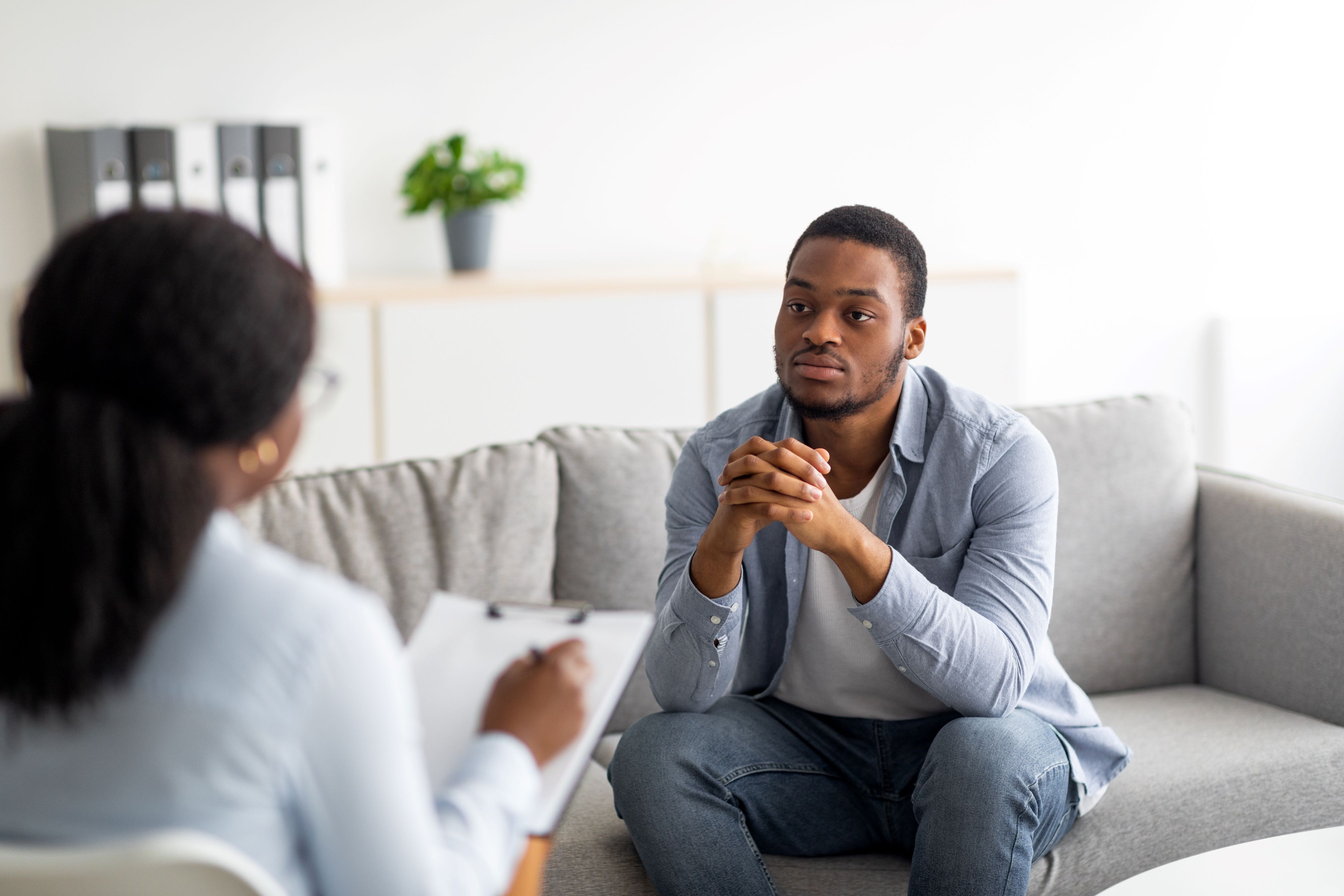 Young black man sits with a health care provider holding a clipboard