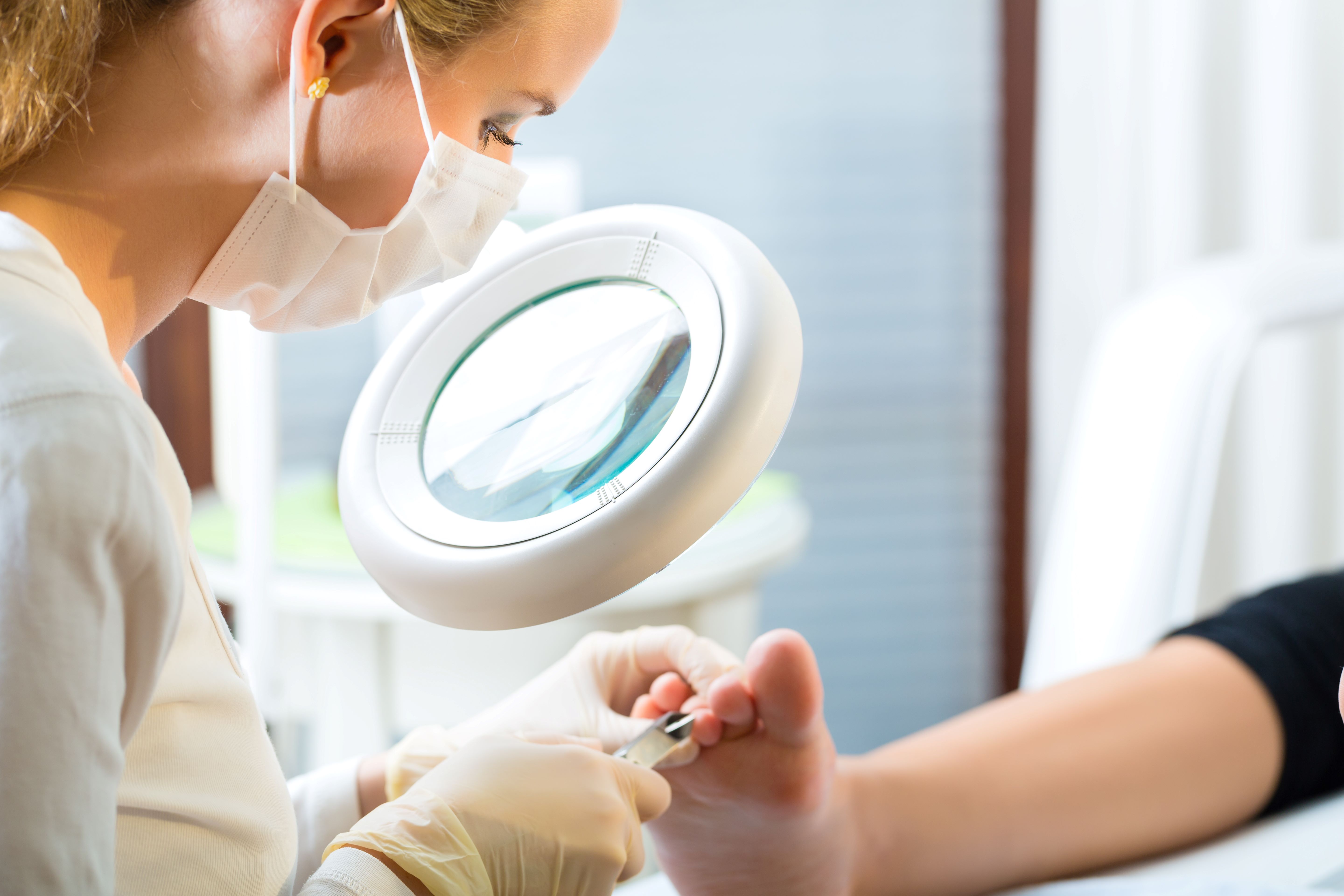 A health care worker looks at a patients foot through a magnifying glass