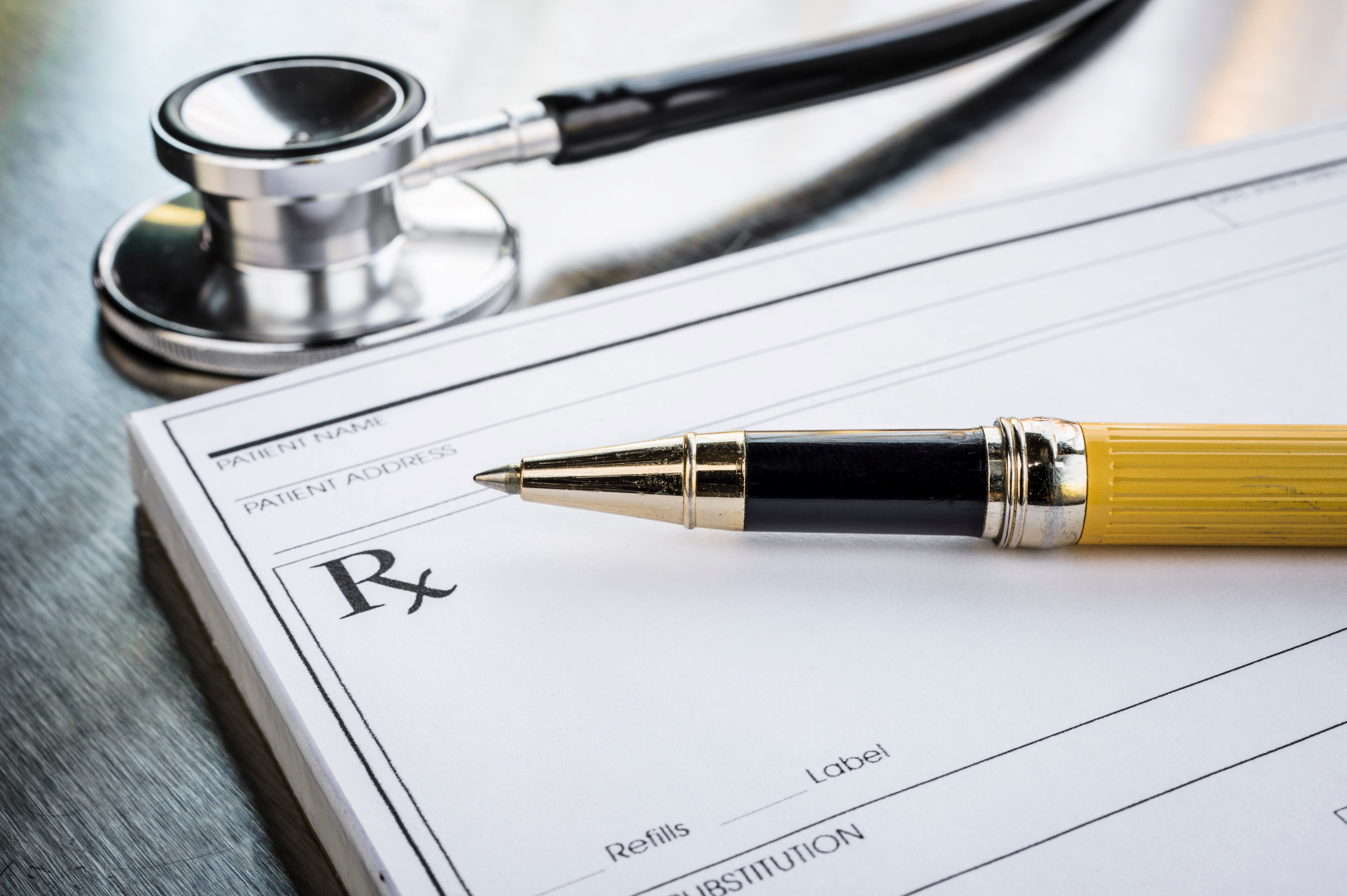 Empty prescription pad with pen and stethoscope in the background