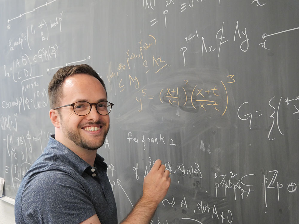 Photo of Associate Professor Ari Shnidman at black board