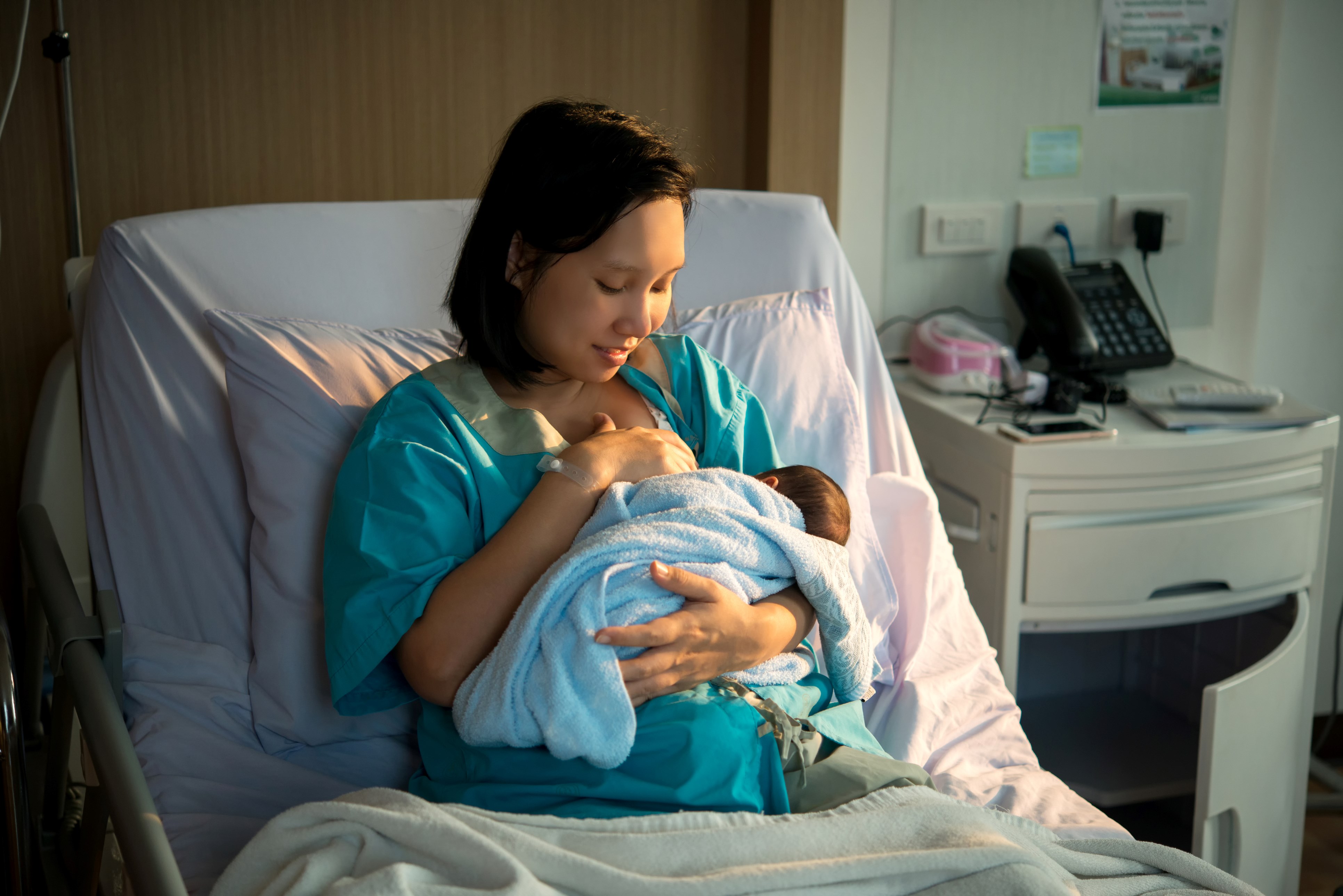 Woman sitting in hospital bed breastfeeds a newborn