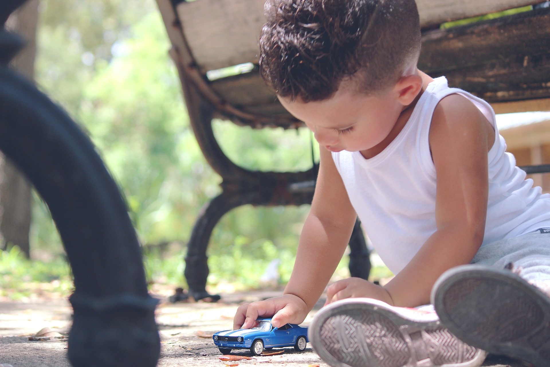 young boy plays with a blue car