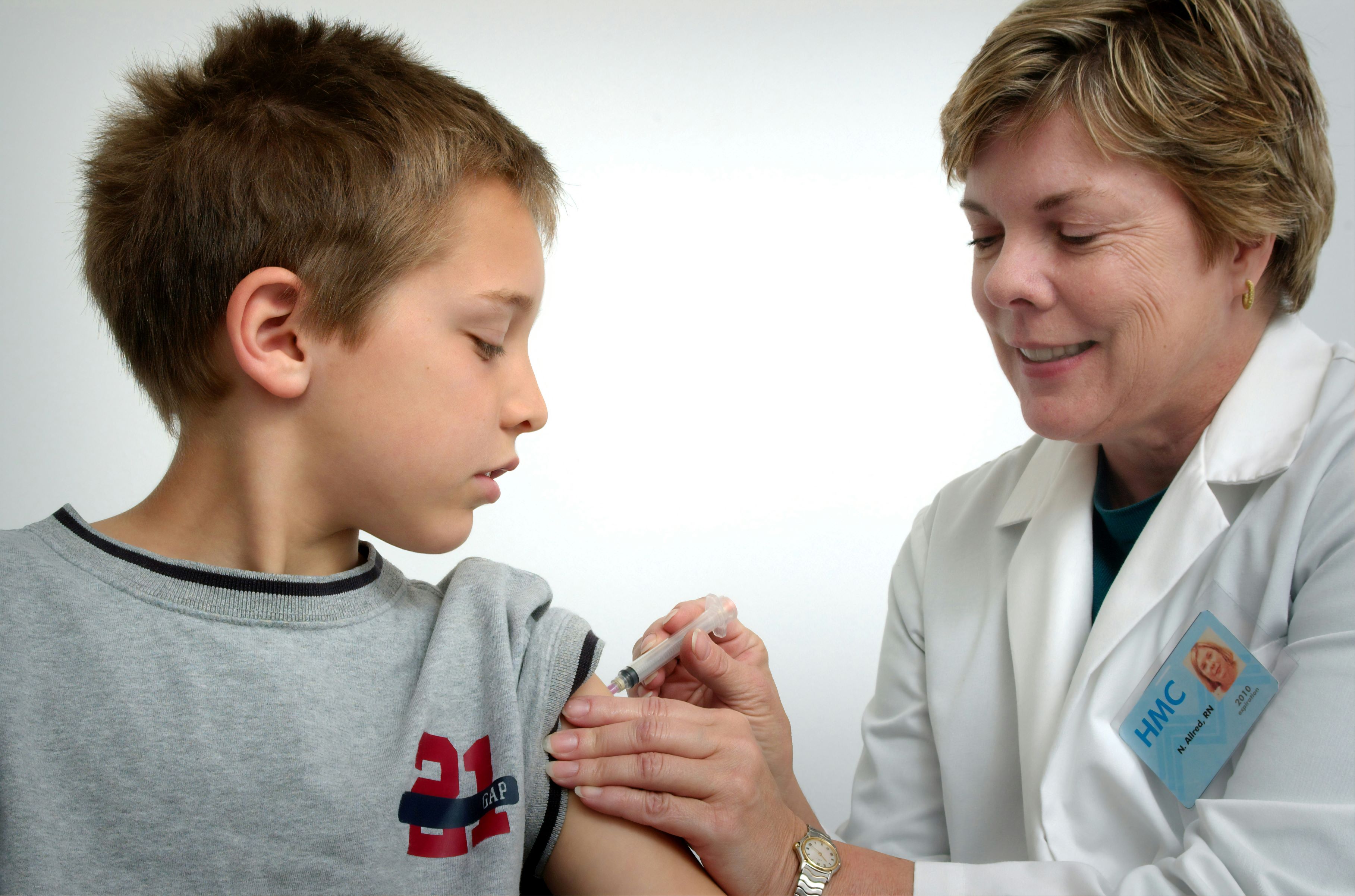 Young boy receives an injection from a woman nurse