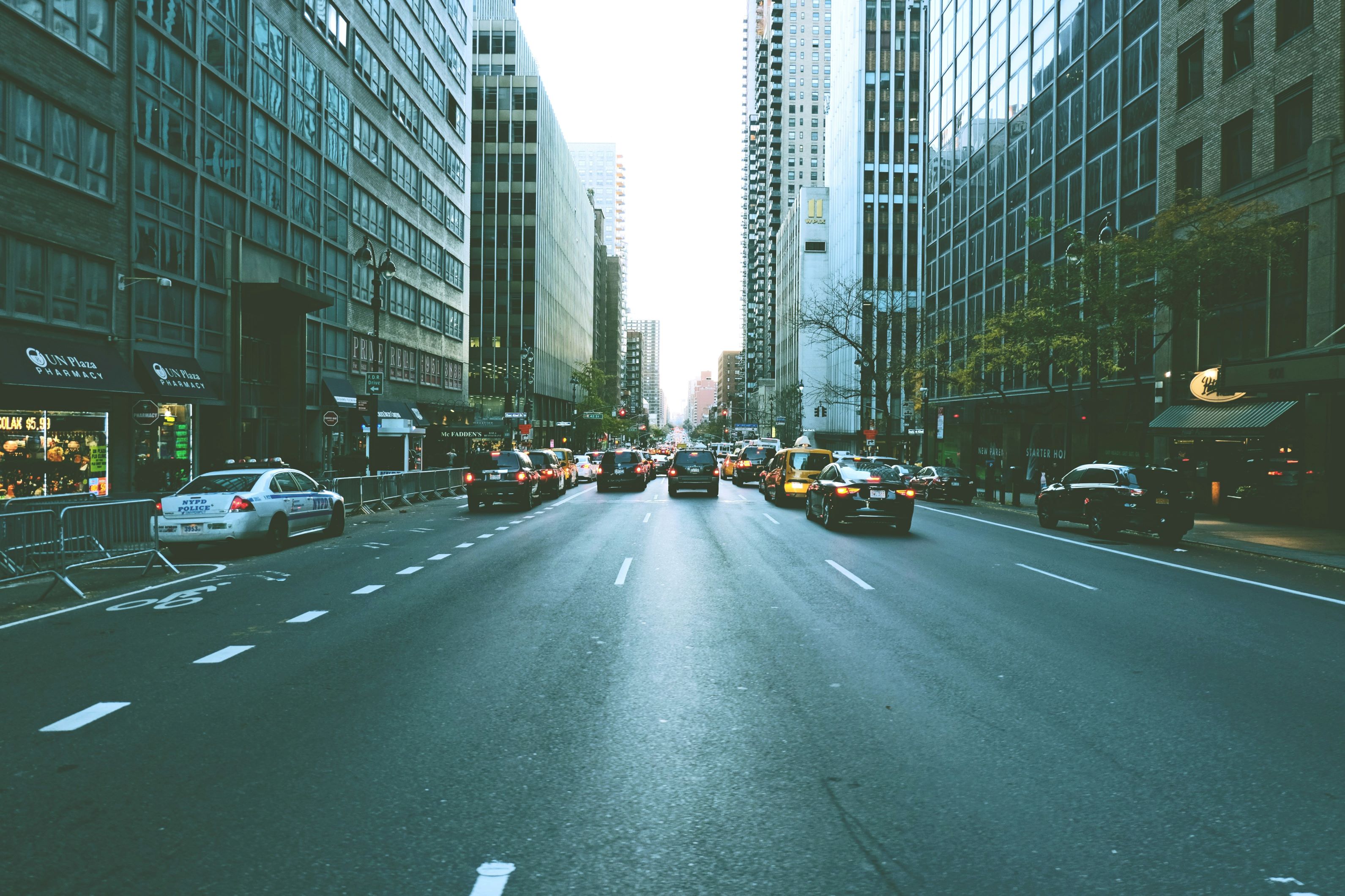 New York City street scene featuring tall buildings on either side, taxis and other cars in the road