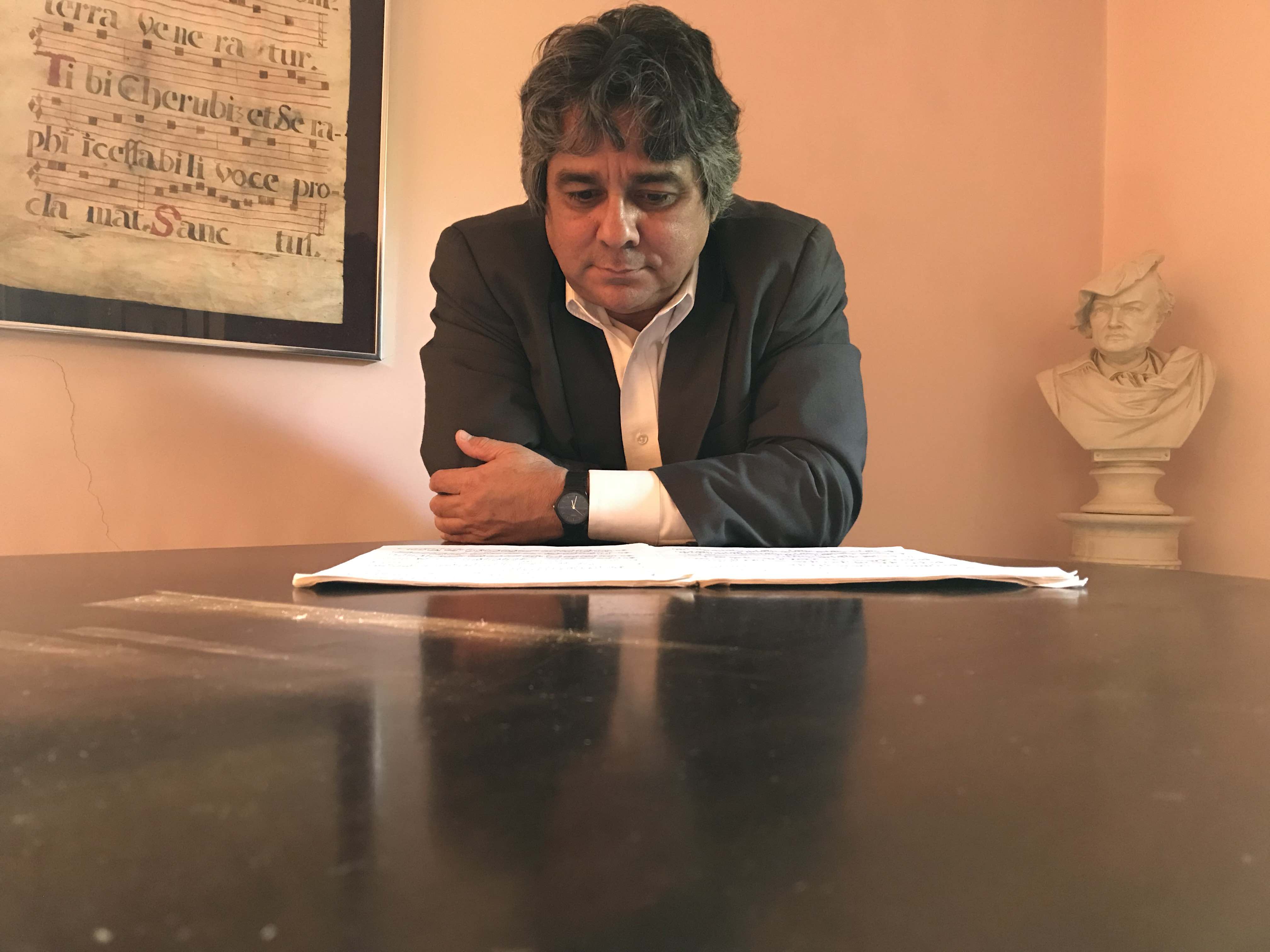 Dr. Emiliano Pardo Tristan is leaning on a piano and reading a score
