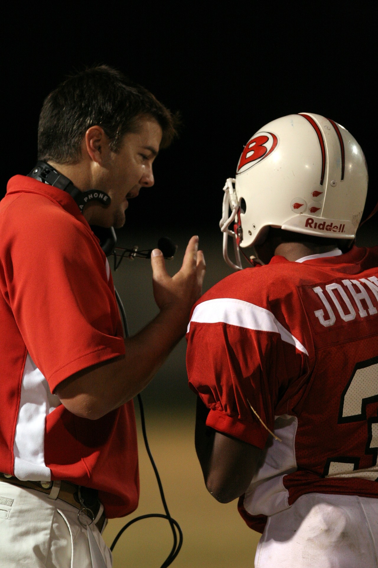 Coach speaks to a player wearing a football helmet