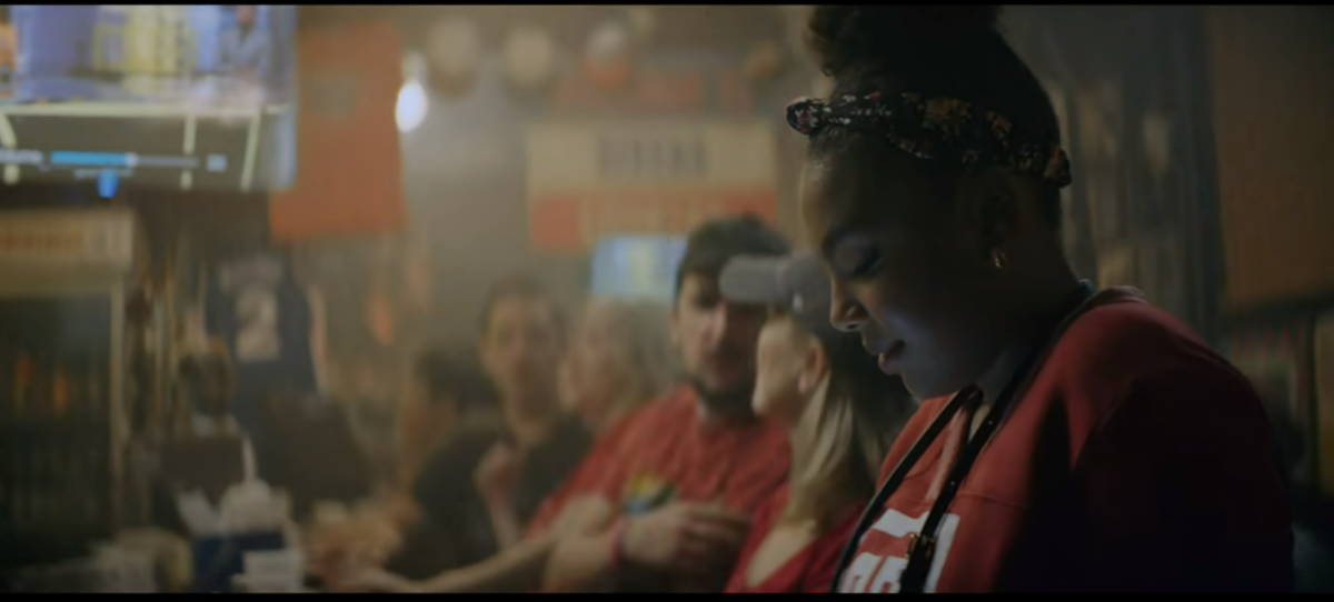 Sugerman's daughter texting her dad while at a bar, wearing a Temple University t-shirt.