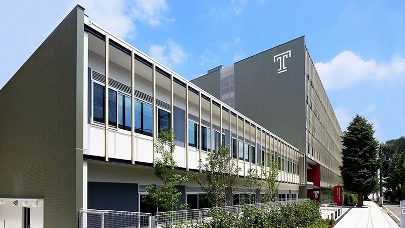 The exterior of a six-story building with a Temple T logo fixated on the top façade.