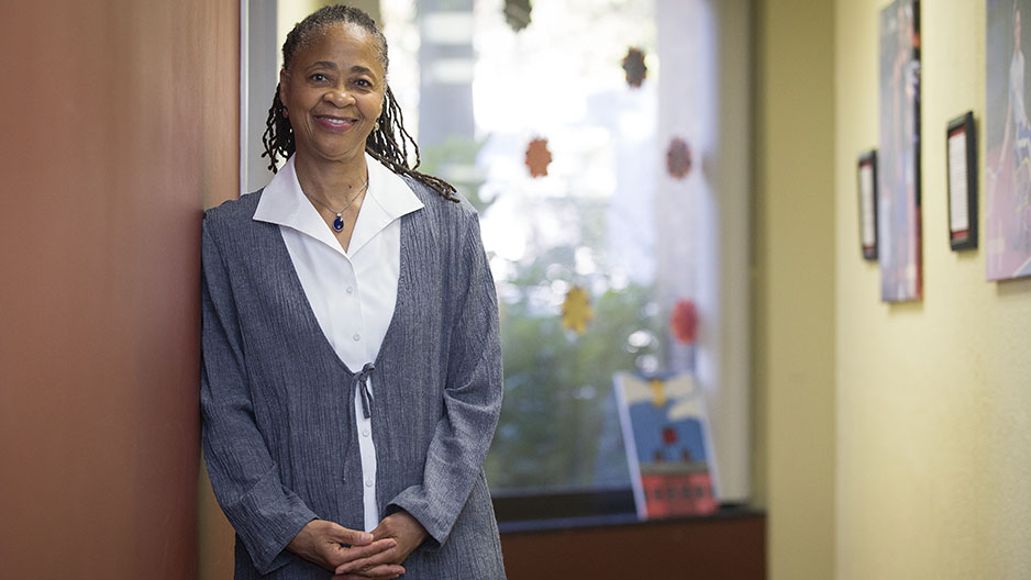 Renee Kirby standing against a wall in her office, smiling. 