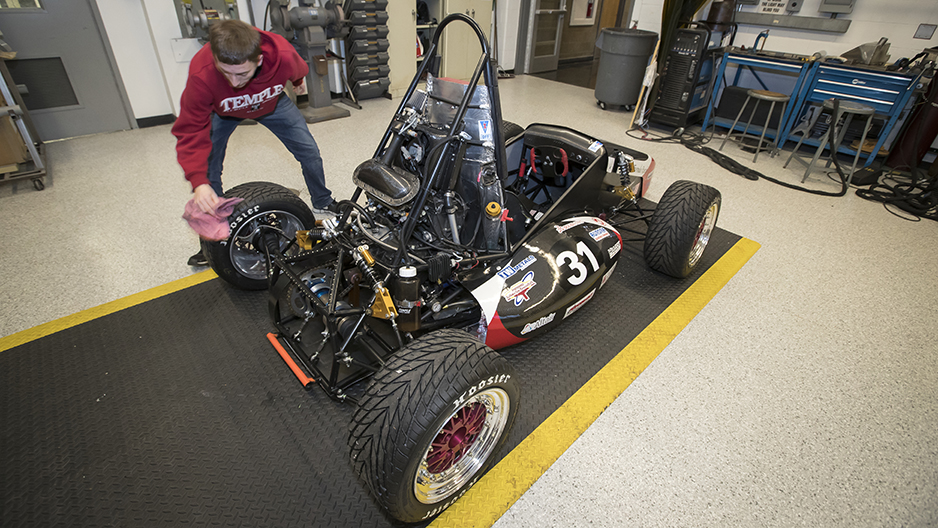 A student cleaning the race car in a workshop. 