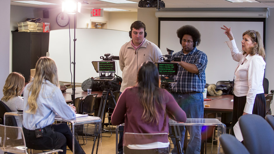 a professor instructing students on a TV news set