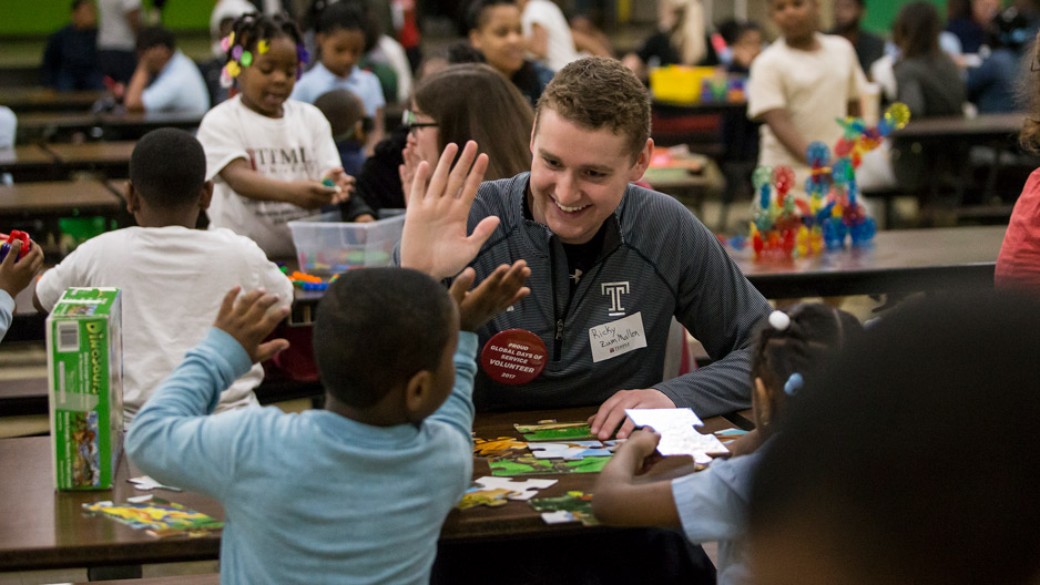 Temple student giving a school child a high five