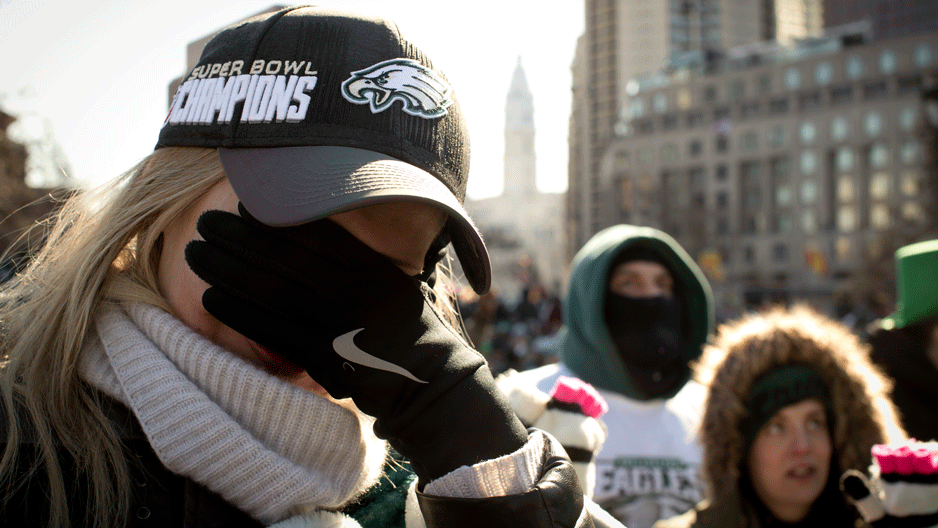 Woman in a Super Bowl champions hat covering face, crying