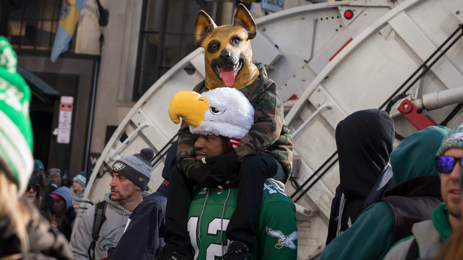 Person in dog mask on shoulders of person wearing Eagles mask