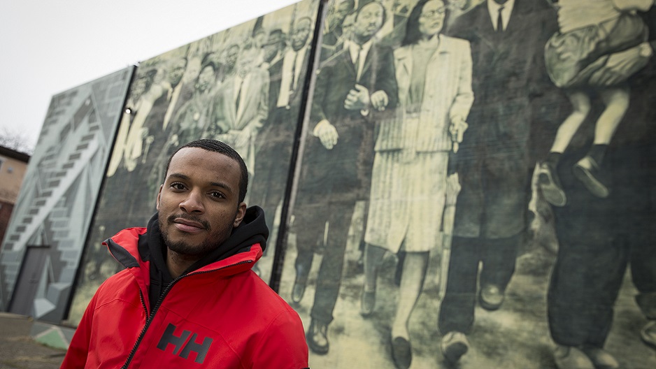 Hazim Hardeman standing in front of a mural near Main Campus. 