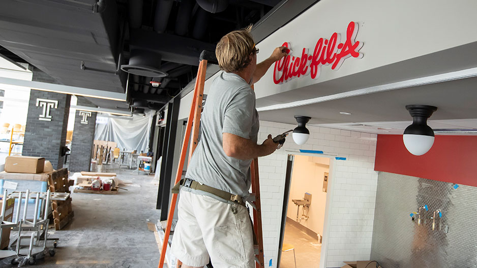 Worker hanging sign at Chick fil A