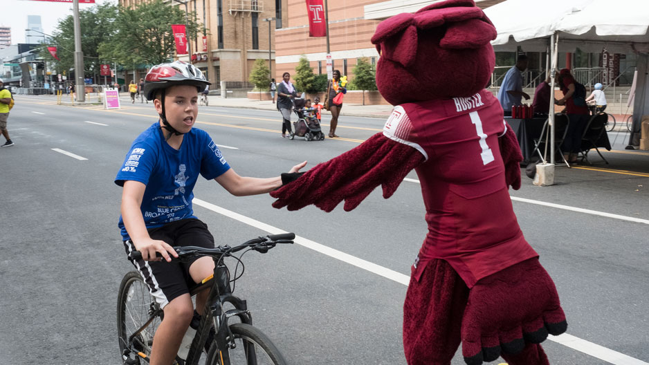 Boy on bike high fives Hooter