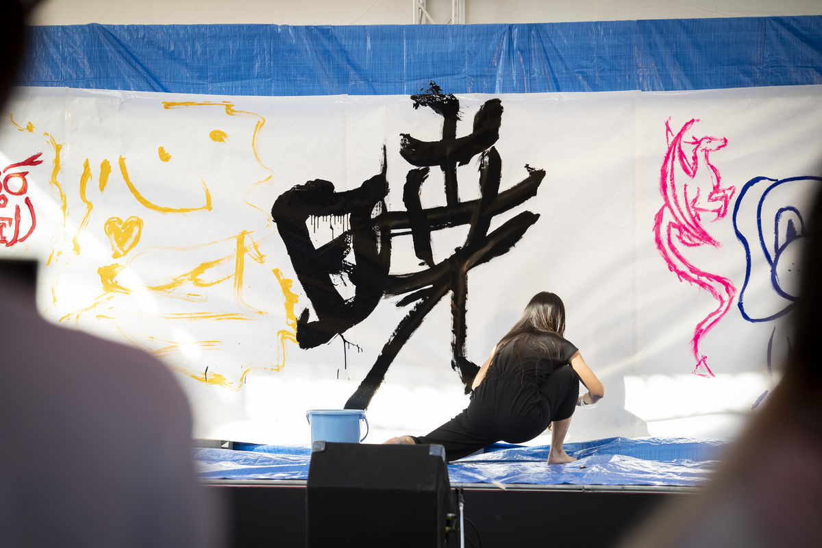 An artists does large-scale Japanese calligraphy during Community Days at TUJ's new campus. 