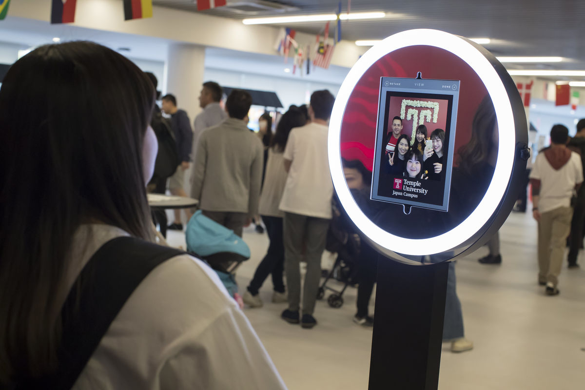 Students have fun taking pictures at a photo booth with a flower Temple "T" as a backdrop. 