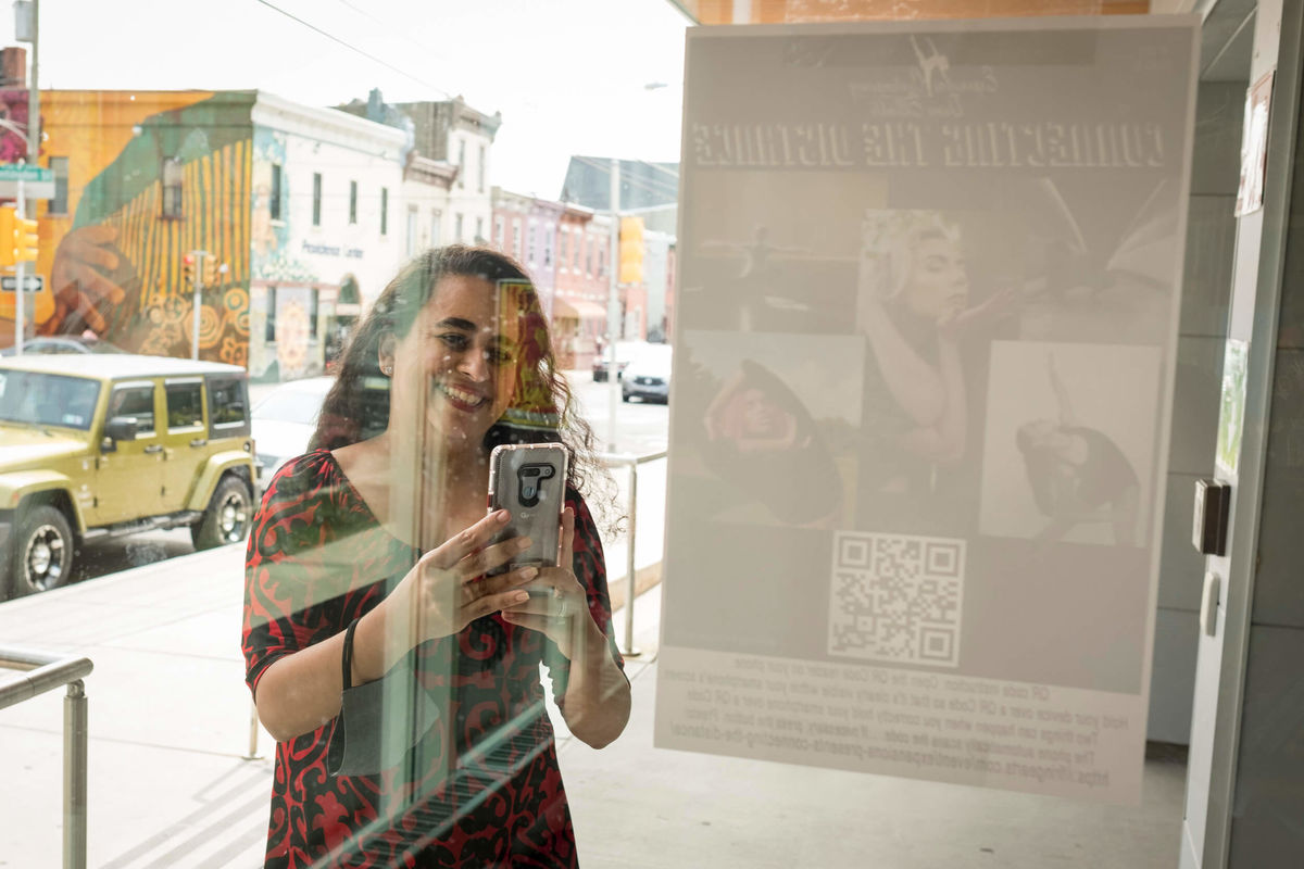 Christina Castro-Tauser watches a virtual performance at one of the destinations on the "Connecting the Distance" walking tour.