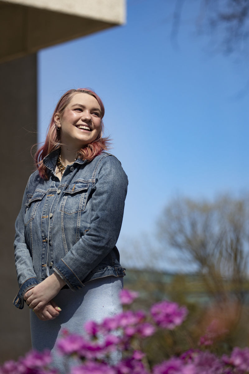 Leeannah McNew standing near purple flowers.