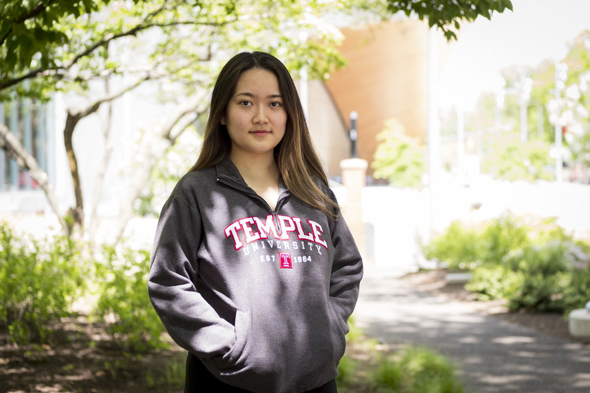 Xirong “Serena” Zhang in a Temple sweatshirt and standing in front of a garden.