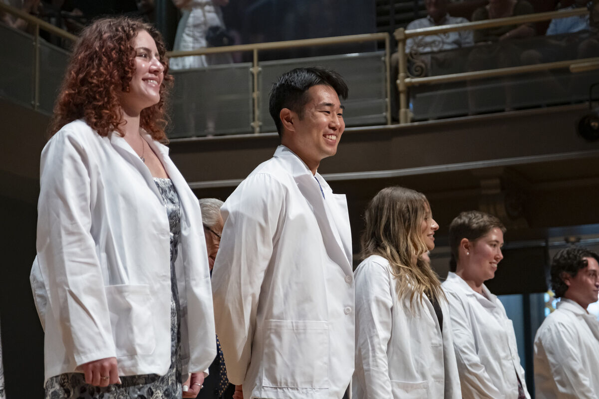 New medical school students celebrate wearing their white coats for the first time