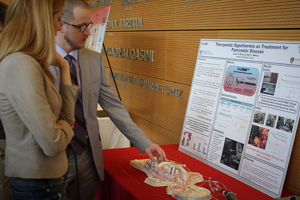 Two people looking at an informational poster about Cool It TempSent. 