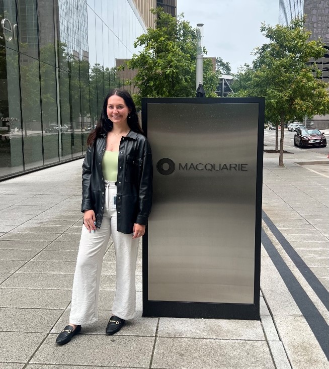 Image of Jackie next to a Macquarie sign in Houston.