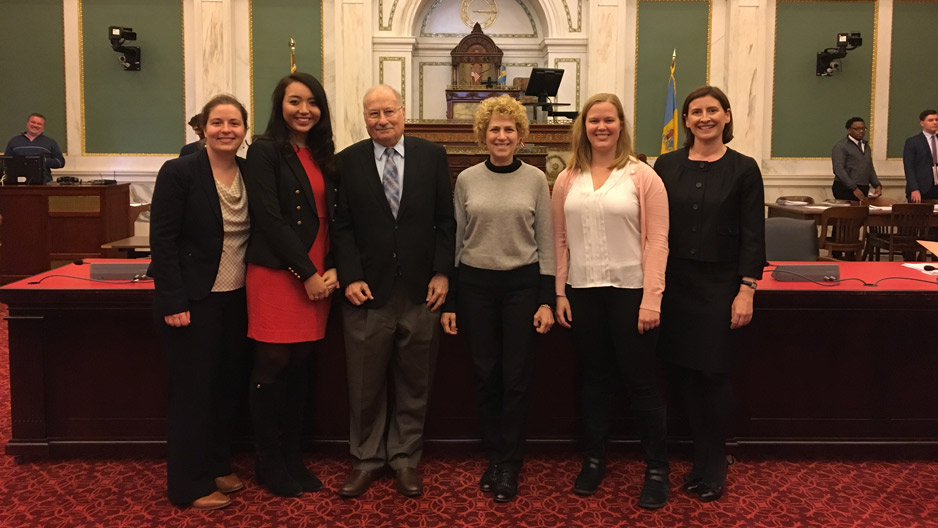 law students, supporters and an associate professor standing in City Council chambers